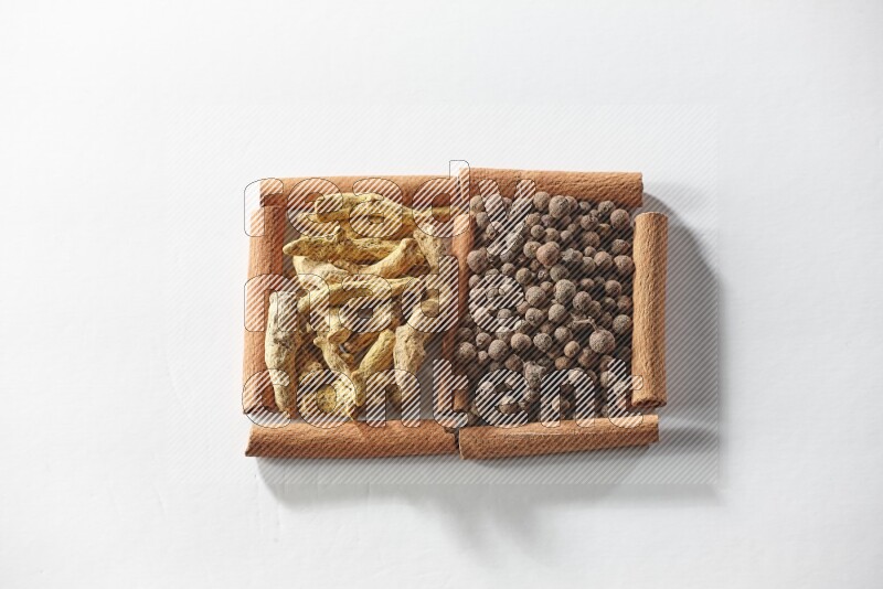 2 squares of cinnamon sticks full of allspice and turmeric fingers on white flooring
