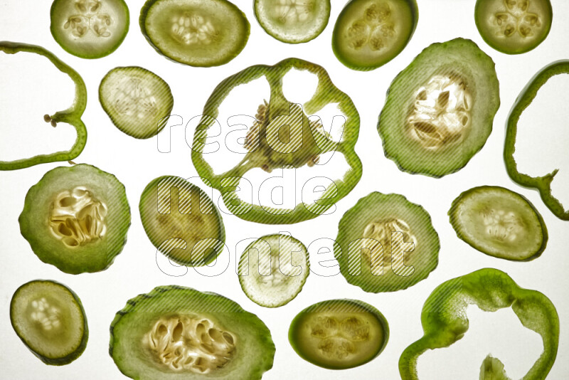 Mixed vegetables and fruits slices on illuminated white background