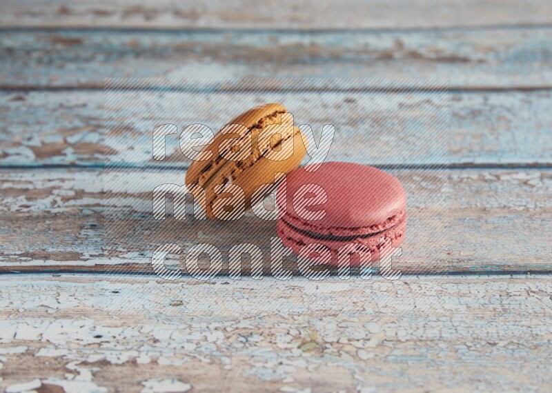 45º Shot of of two assorted Brown Irish Cream, and Pink Raspberry macarons on light blue background