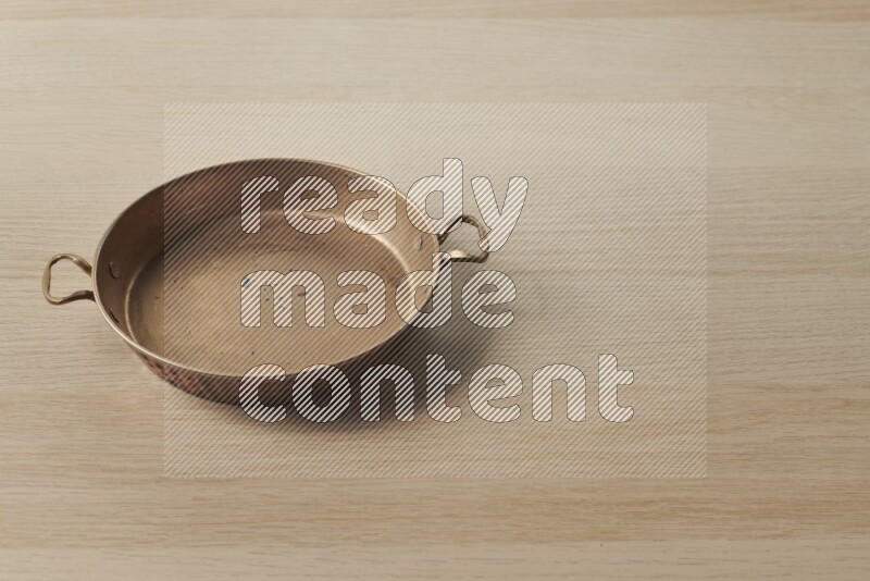 A small copper pan on light wooden background