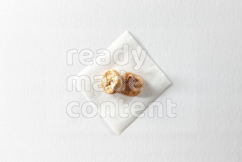 Two dried figs on a piece of paper on a white background in different angles