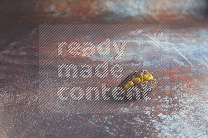 one pistachio stuffed madjoul date on a rustic reddish background