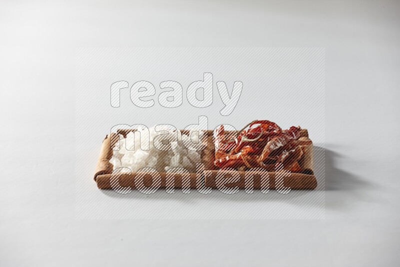 2 squares of cinnamon sticks full of dried red chilis and white salt on white flooring