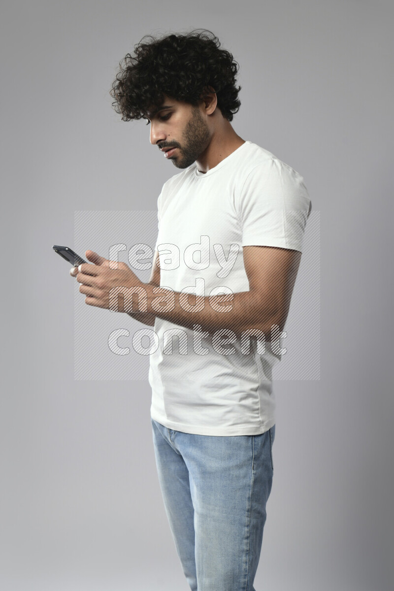 A man wearing casual standing and browsing on the phone on white background
