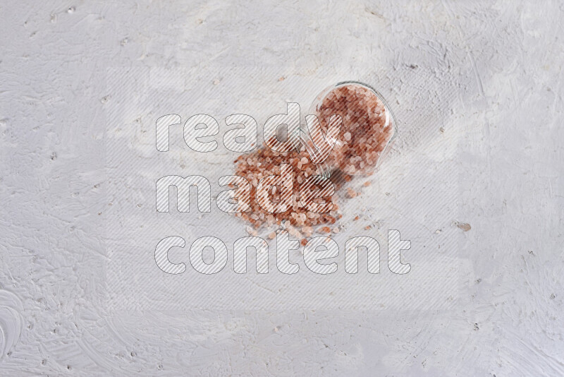 A glass jar full of coarse himalayan salt crystals on white background