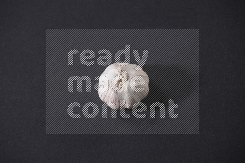 A whole garlic bulb placed on a black flooring