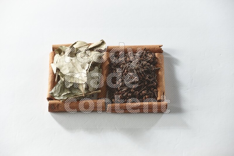 2 squares of cinnamon sticks full of cloves and bay laurel leaves on white flooring