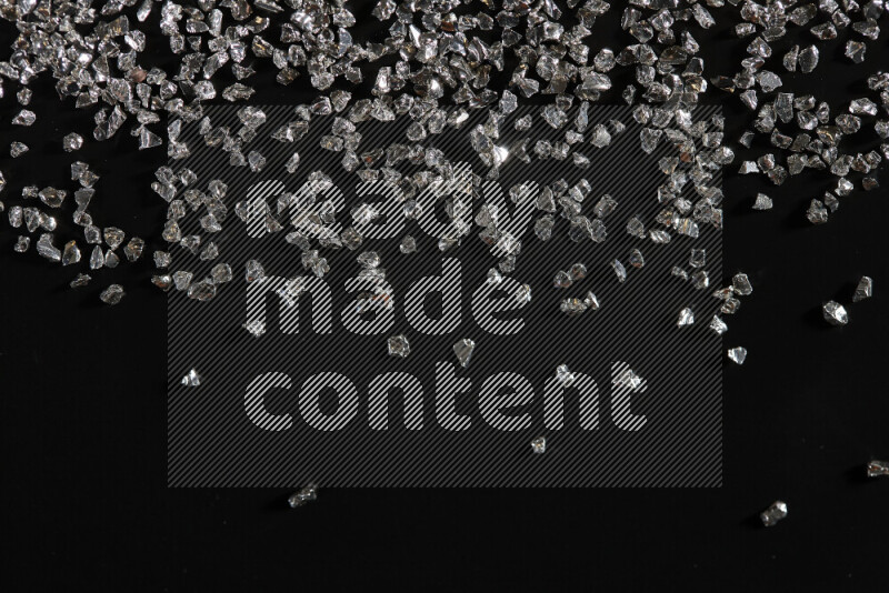 قطع زجاجية فضية لامعة متناثرة على خلفية سوداء