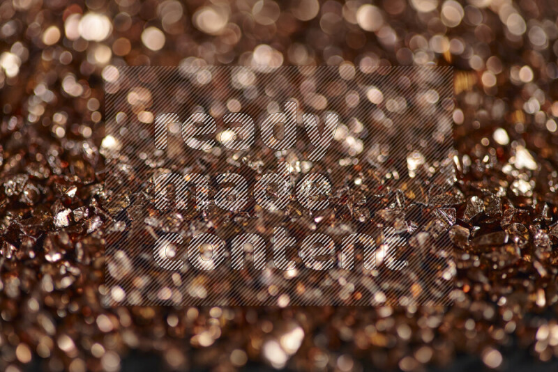 Bronze shimmering fragments of glass scattered on a black background