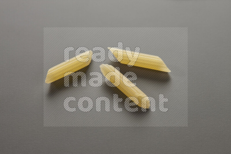 Mini penne pasta on grey background