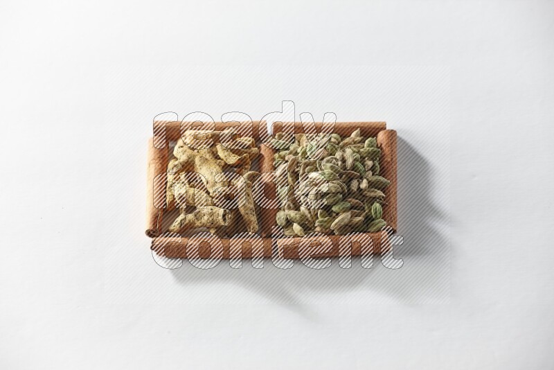 2 squares of cinnamon sticks full of cardamom and turmeric fingers on white flooring