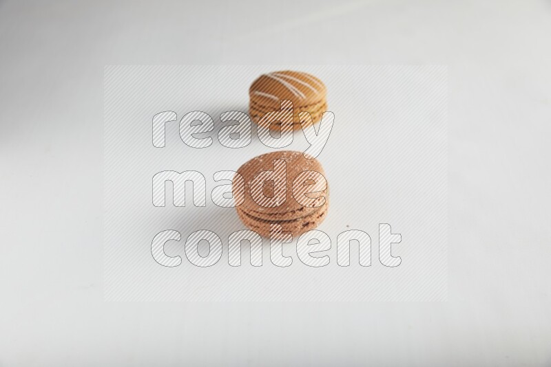 45º Shot of of two assorted Brown Irish Cream, and Brown Hazelnuts macarons on white background