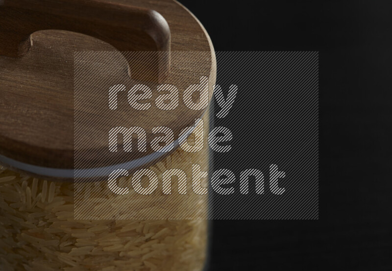 Basmati golden rice in a glass jar on black background
