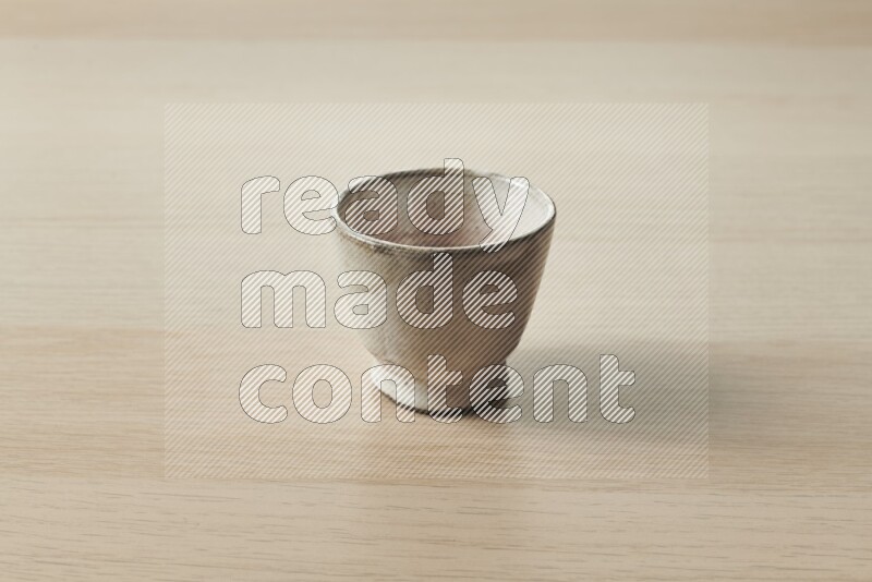 A pottery cup on light wooden background