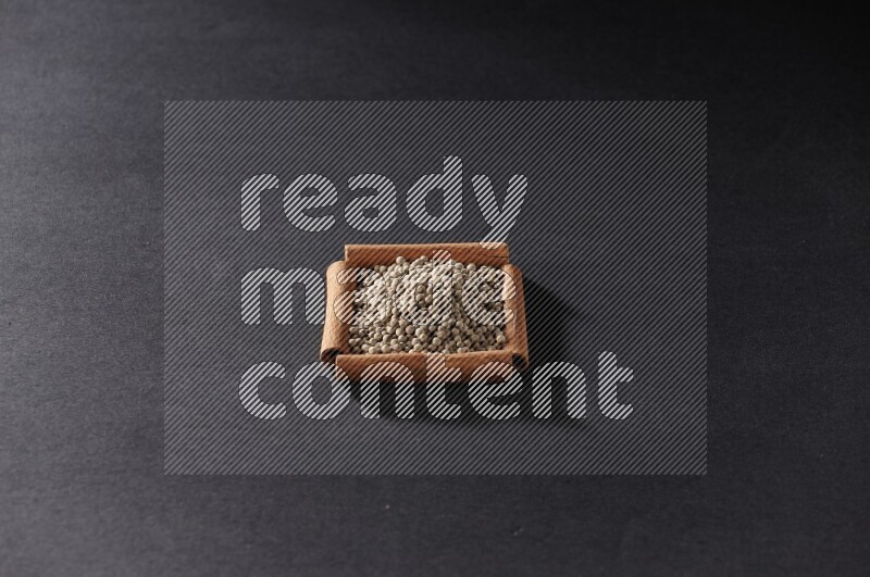 A single square of cinnamon sticks full of white pepper on black flooring