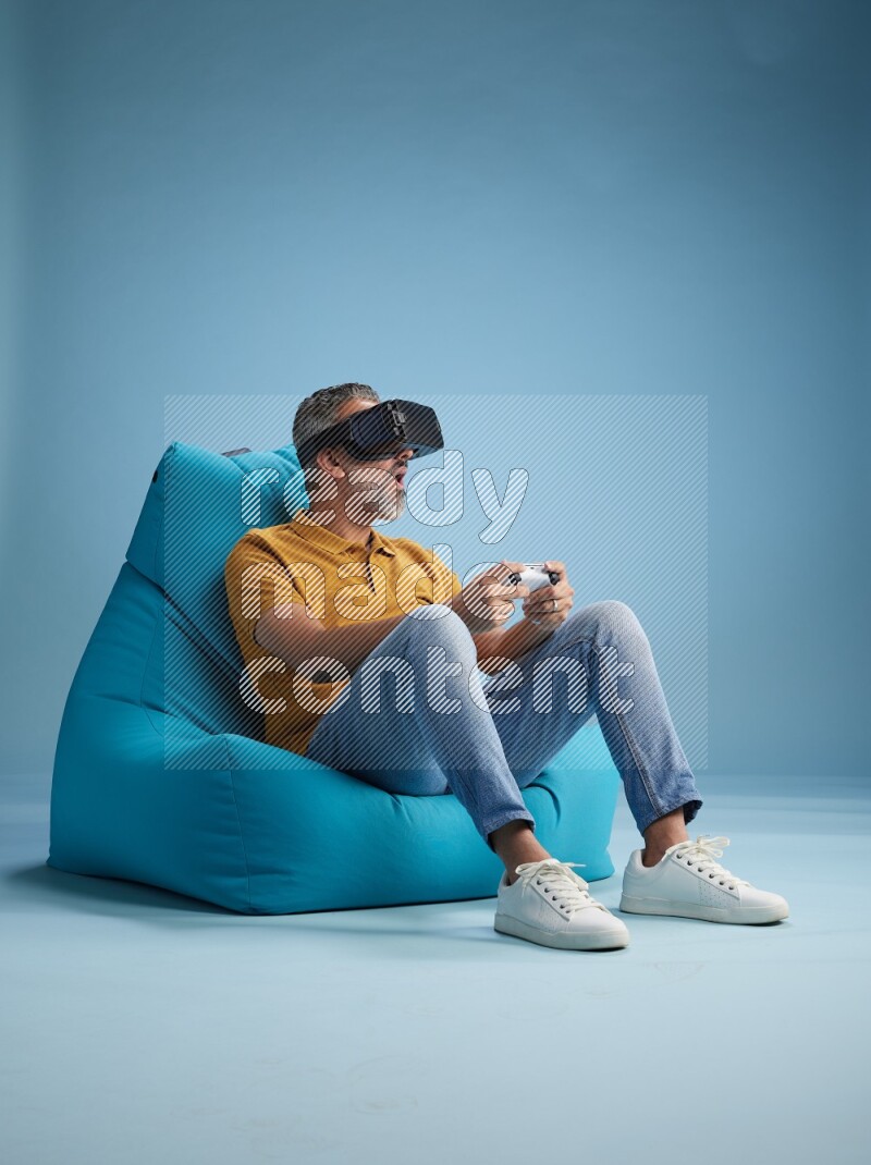 A man sitting on a blue beanbag and gaming with VR