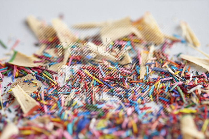 This image showcases a vibrant multicolored pencil shavings scattered on grey background