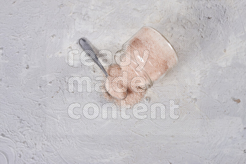 A glass jar full of fine himalayan salt on white background