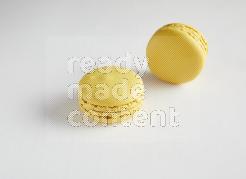 45º Shot of two Yellow Lemon macarons on white background