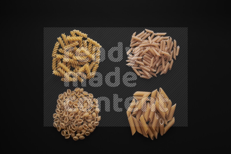 Different pasta types in bunches on black background