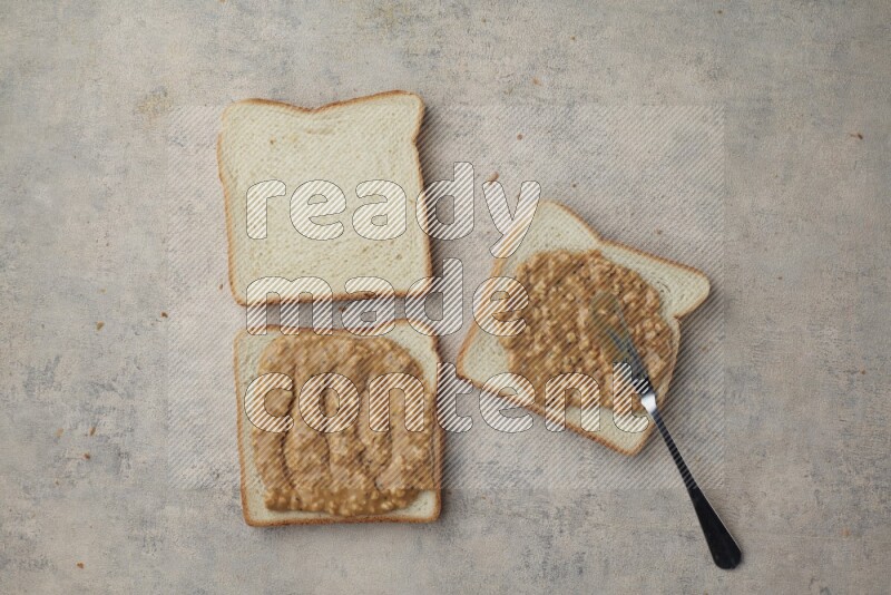 crunchy peanut butter on white toast and white toast slices on a light blue textured background