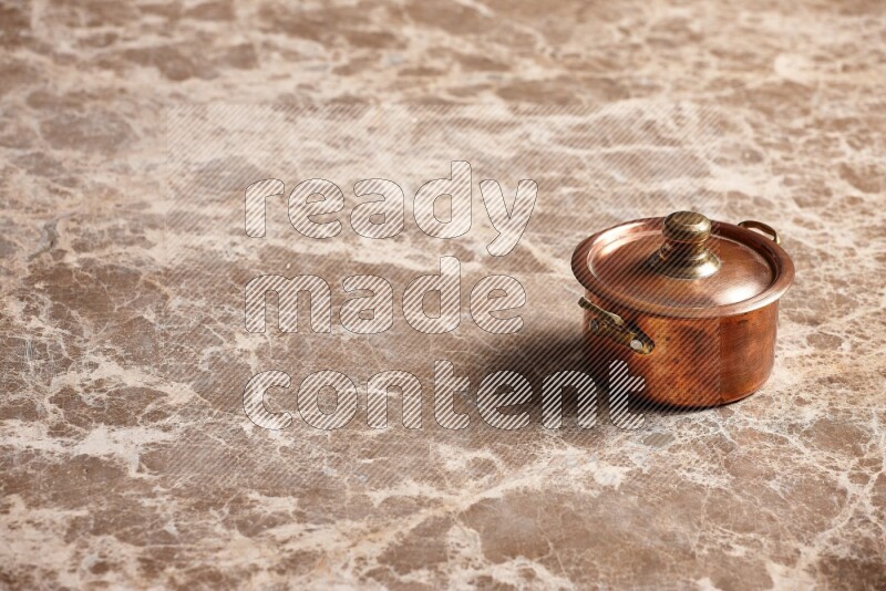 A small copper pot on beige marble background