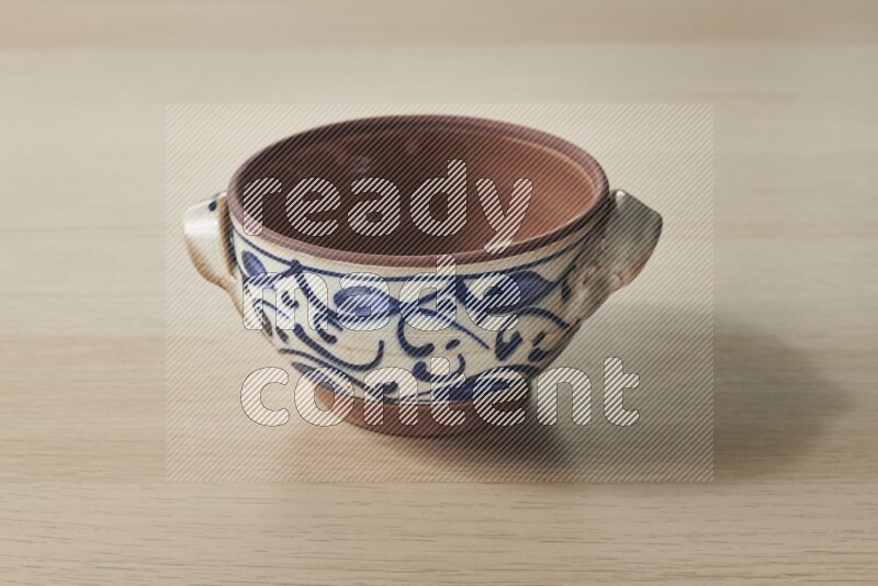 A multicolored pottery pot on light wooden background