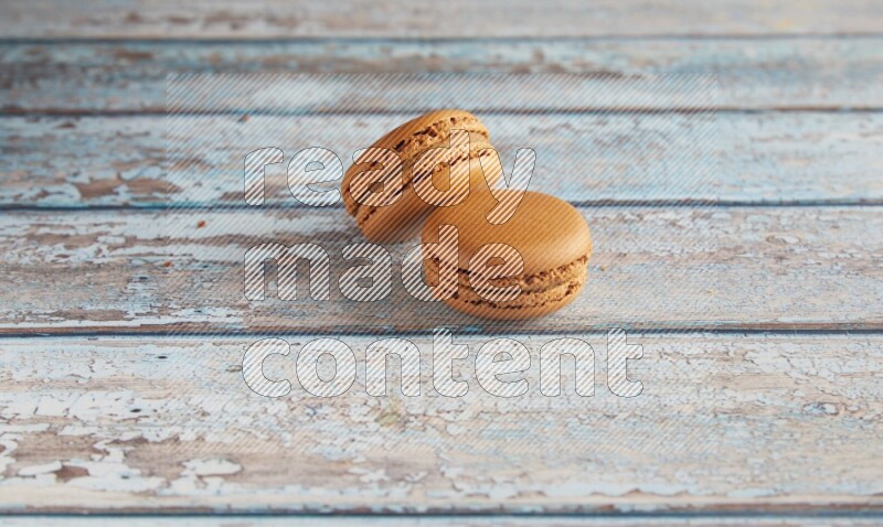 45º Shot of two Brown Maple Taffy macarons on light blue wooden background