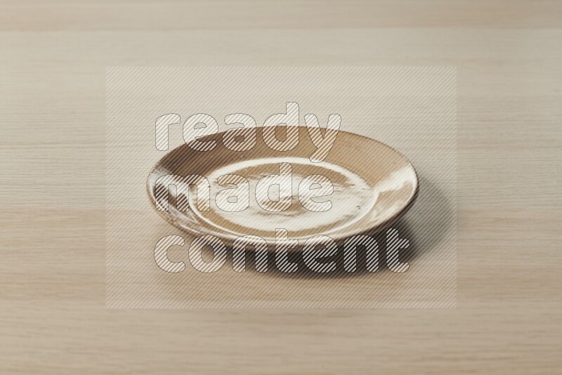 A beige pottery plate on light wooden background