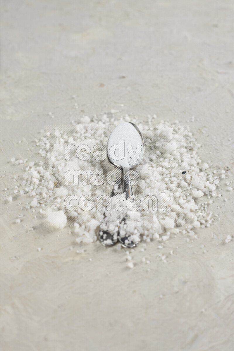 2 metal spoons filled with fine table salt and fine pink himalayan salt on white background