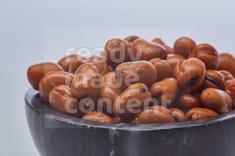 Close up shot of cooked fava beans (foul) in a container on white background