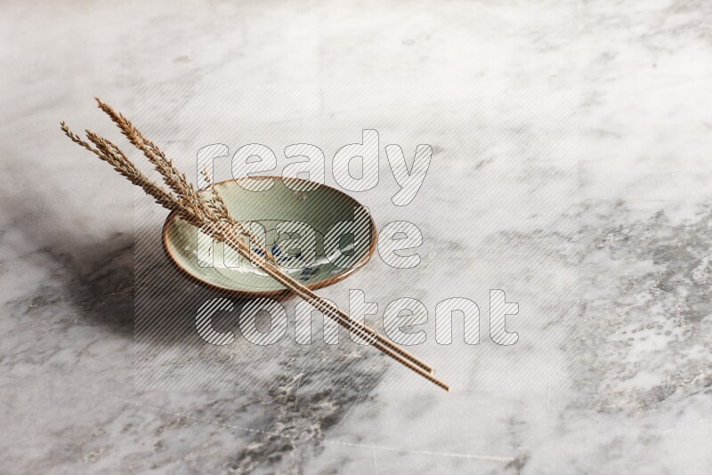 Wheat stalks on decorative pottery plate on grey marble background