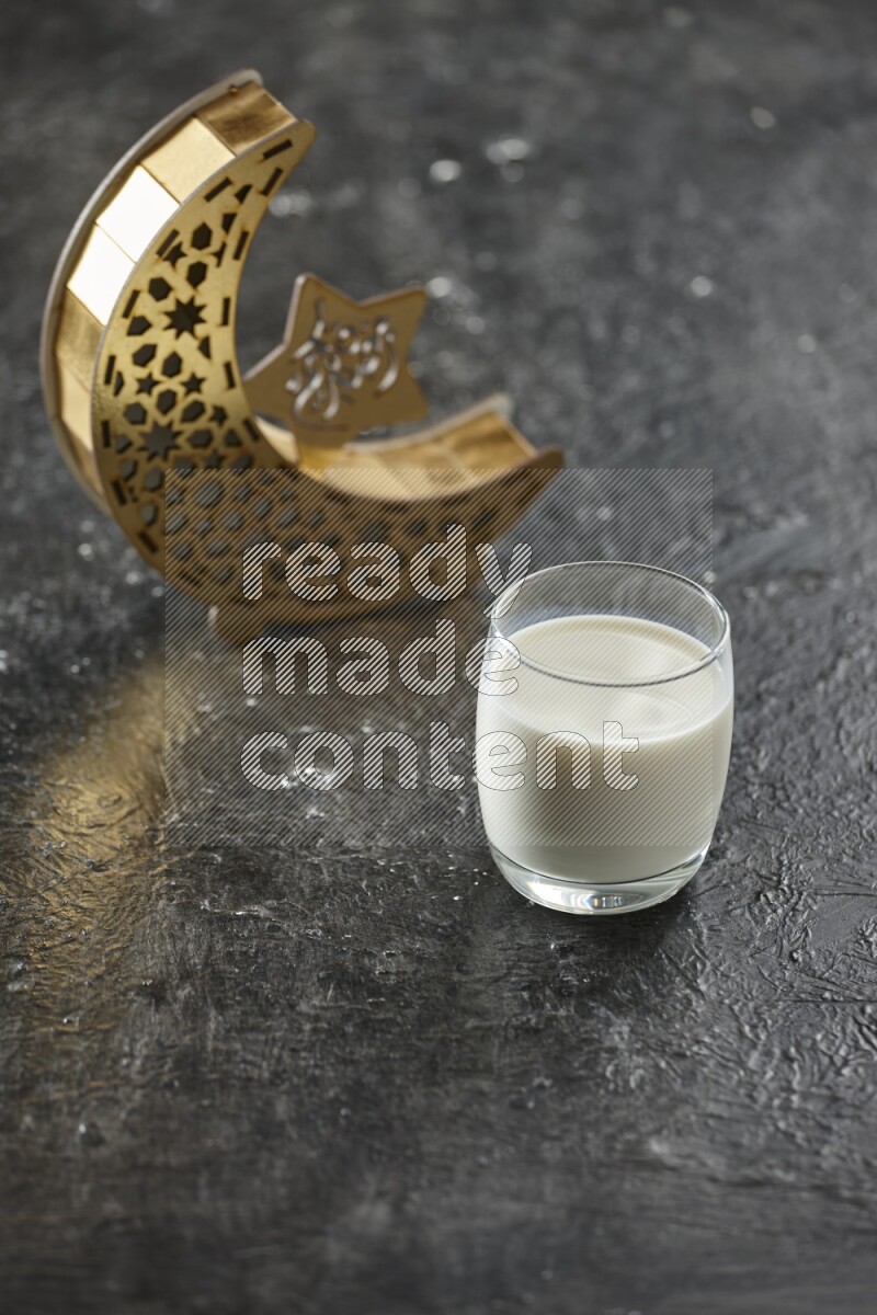 فانوس خشبي هلالي باللون الذهبي مع مشروبات مختلفة وتمر ومكسرات وسبحة صلاة وقرآن على خلفية سوداء