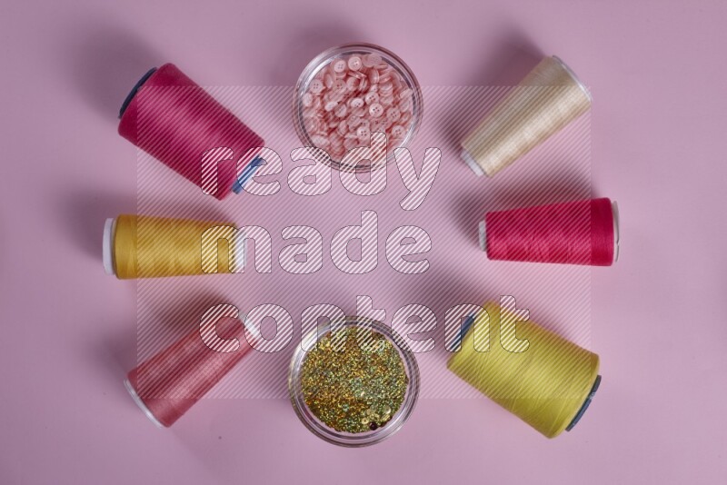 مجموعة من أدوات الخياطة والتفصيل صفراء وزهرية اللون على خلفية زهرية