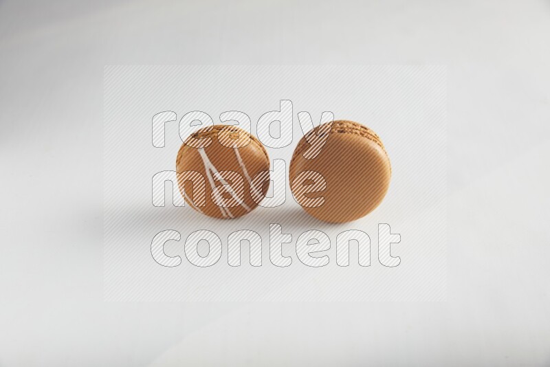 45º Shot of of two assorted Brown Irish Cream, and Brown Maple Taffy macarons  on white background
