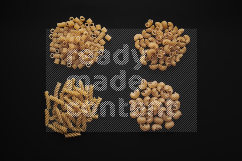 Different pasta types in bunches on black background