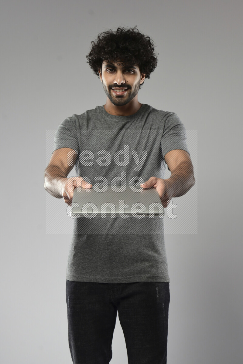A man wearing casual standing and holding a laptop on white background