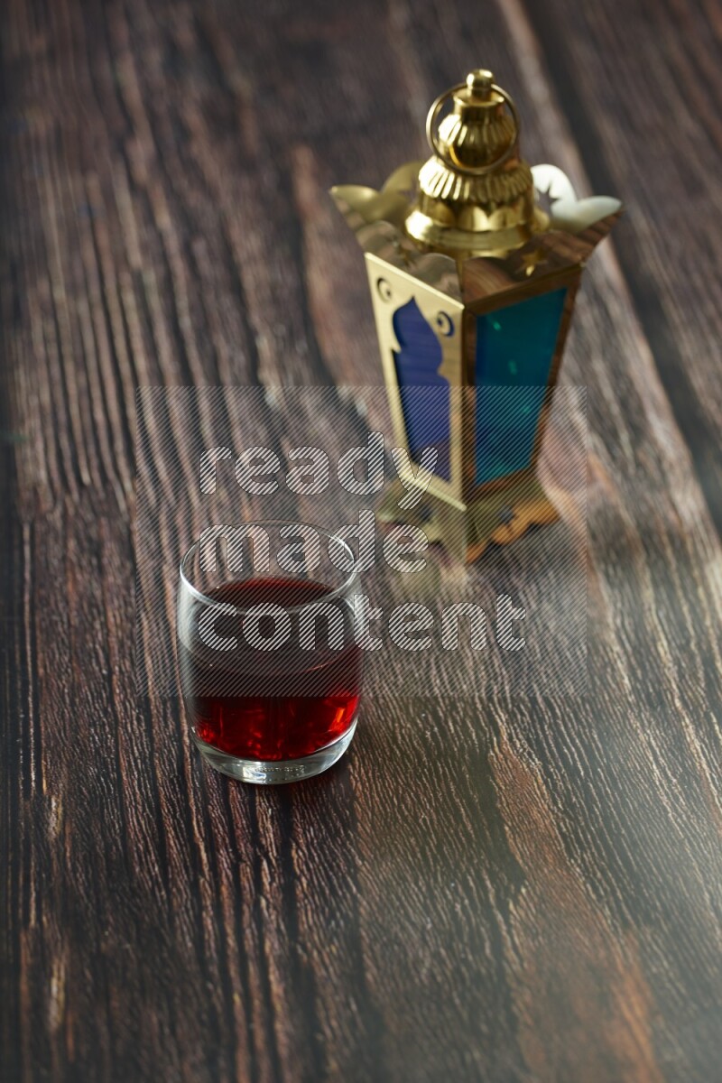 A golden lantern with different drinks, dates, nuts, prayer beads and quran on brown wooden background