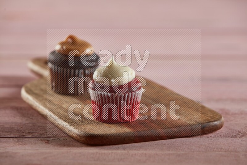Red velvet mini cupcake topped with cream on a wooden board