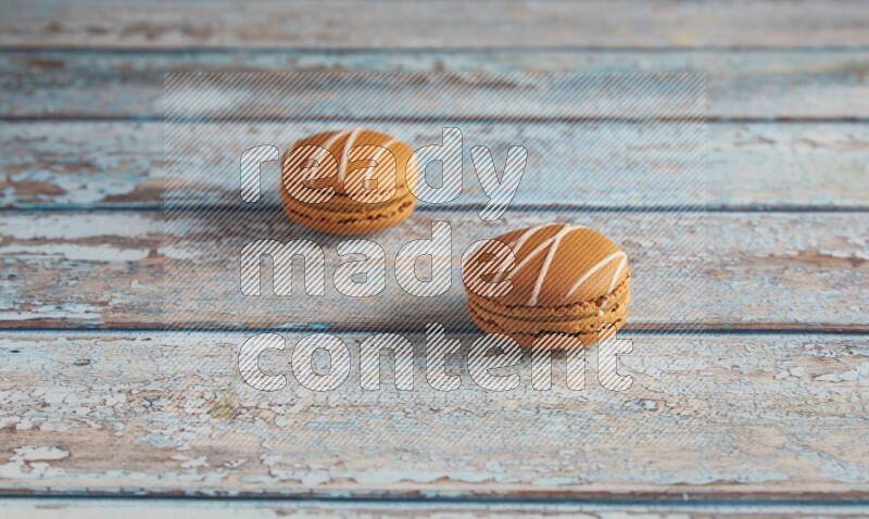 45º Shot of two Brown Irish Cream macarons on a  light blue wooden background