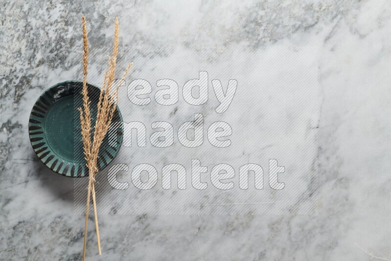 Wheat stalks on multicolored pottery plate on grey marble background