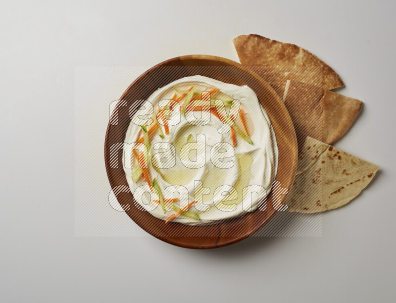 Lebnah garnished with sliced carrots & cucumber in a wooden plate on a white background