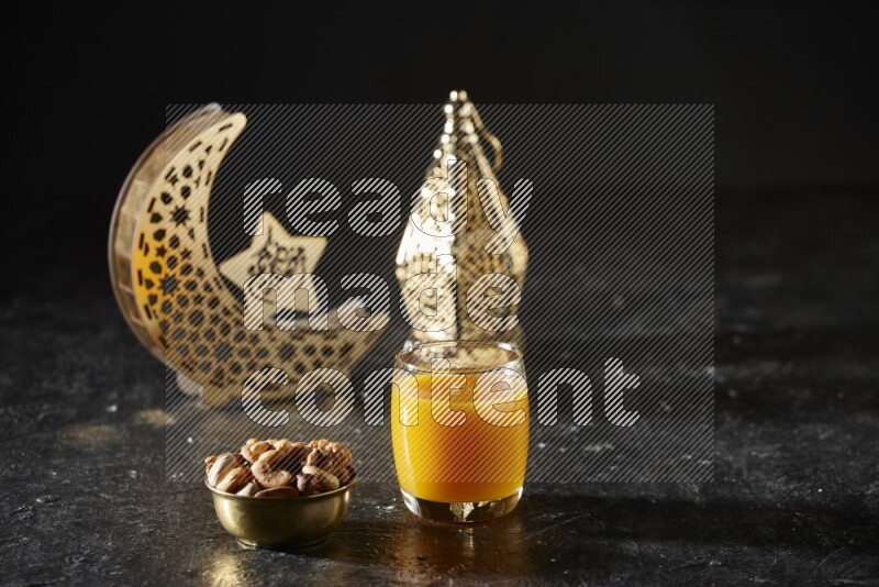 Nuts in a metal bowl with qamar el din beside golden lanterns in a dark setup