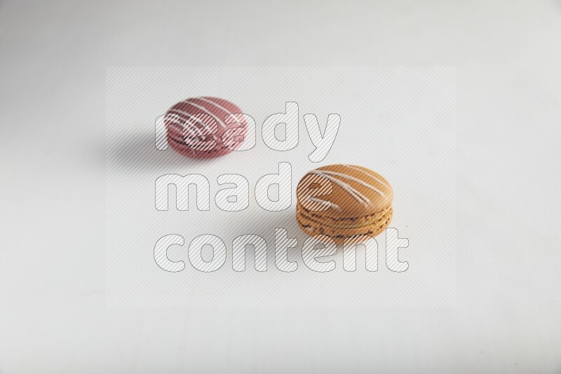 45º Shot of of two assorted Brown Irish Cream, and Red Poppy Flower macarons on white background