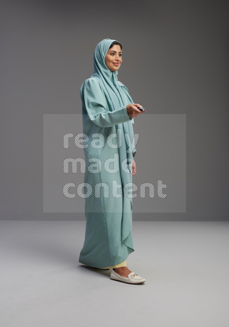 Saudi Woman wearing Abaya standing holding car key on Gray background