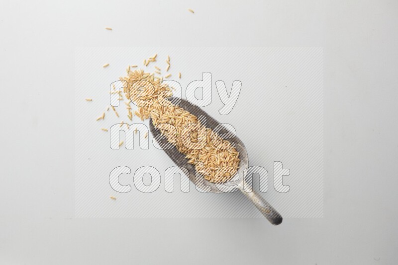 Top-view of a long grain brown rice, and shovel on white background