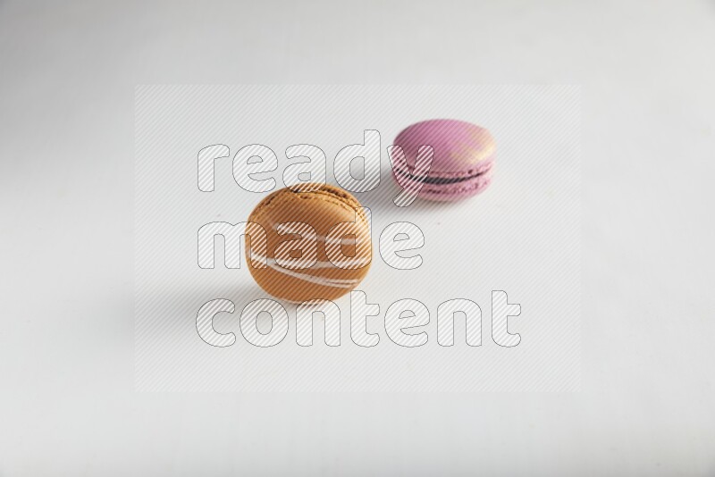 45º Shot of of two assorted Brown Irish Cream, and Purple Strawberry macarons on white background