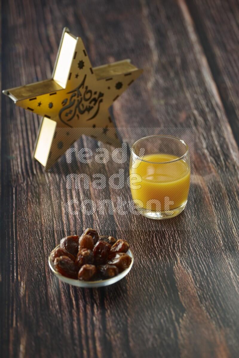 A wooden golden star lantern with different drinks, dates, nuts, prayer beads and quran on brown wooden background