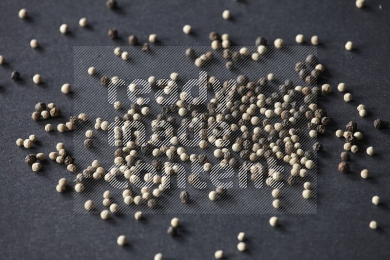 حبوب الفلفل المختلطة السوداء والبيضاء على أرضية سوداء