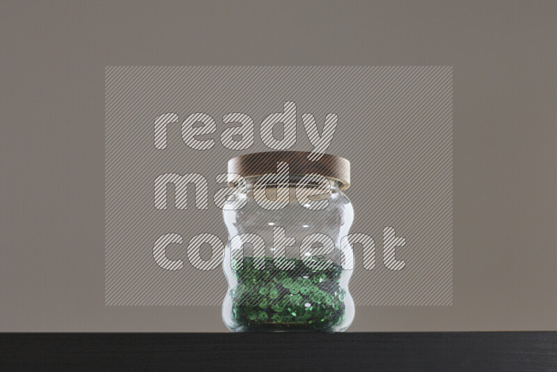 Sequins in a glass jar on black background